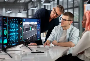 Three security professionals review 3D data center infrastructure and analytics dashboards on dual monitors in a modern of...
